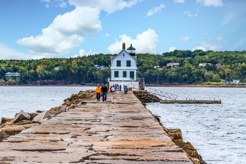 people walking on the rockland breakwall to the lighthouse